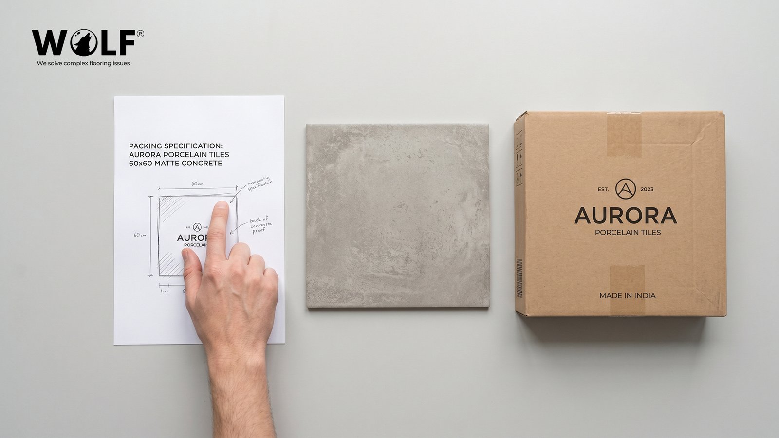 Flat lay showing a packing specification sheet for Aurora porcelain tiles, a matte concrete tile sample, and a branded carton marked Made in India, representing the private label process