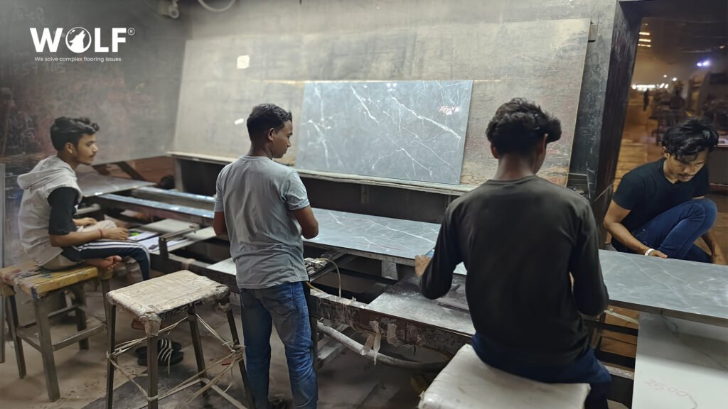 Factory staff checking a grey marble-look porcelain tile at an inspection table for shade and finish sign-off