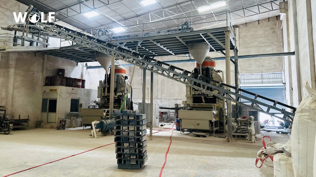 Tile presses fed by an overhead powder conveyor at Wolf's porcelain factory in Morbi, India
