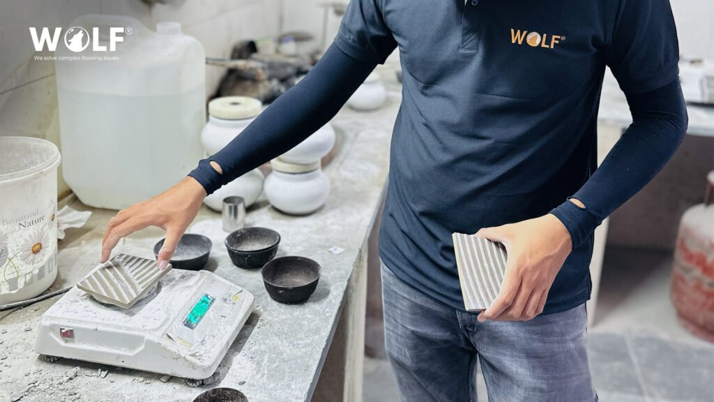 Wolf technician weighing a porcelain tile sample on a factory scale during a pre-shipment quality check