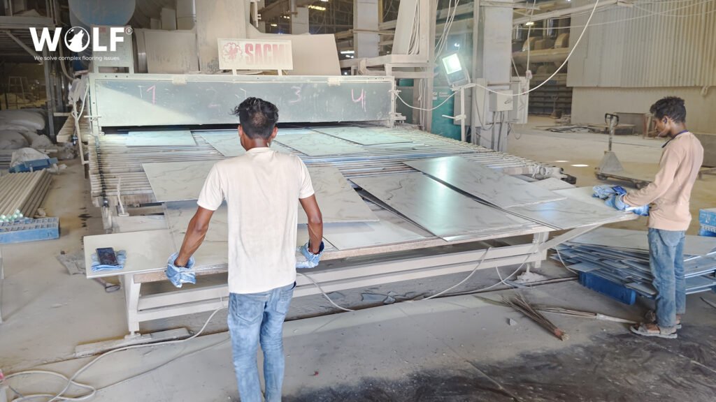 Two factory workers handling large-format porcelain tiles on a roller line at a Wolf porcelain tile factory