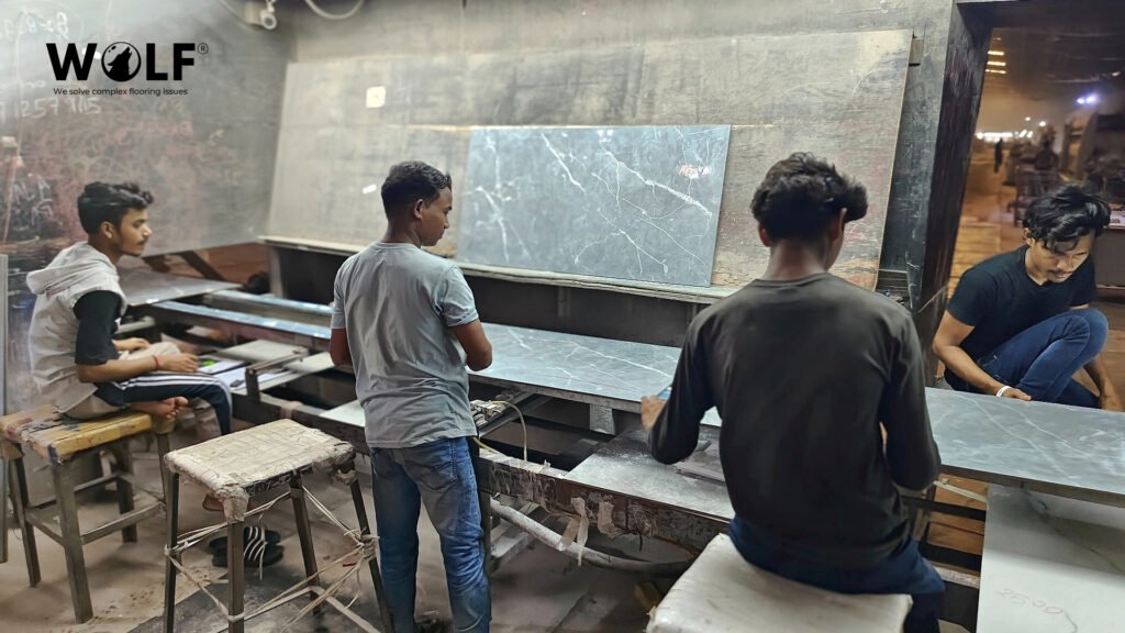 Wolf team inspecting a grey marble-look porcelain tile at the sorting table in Morbi