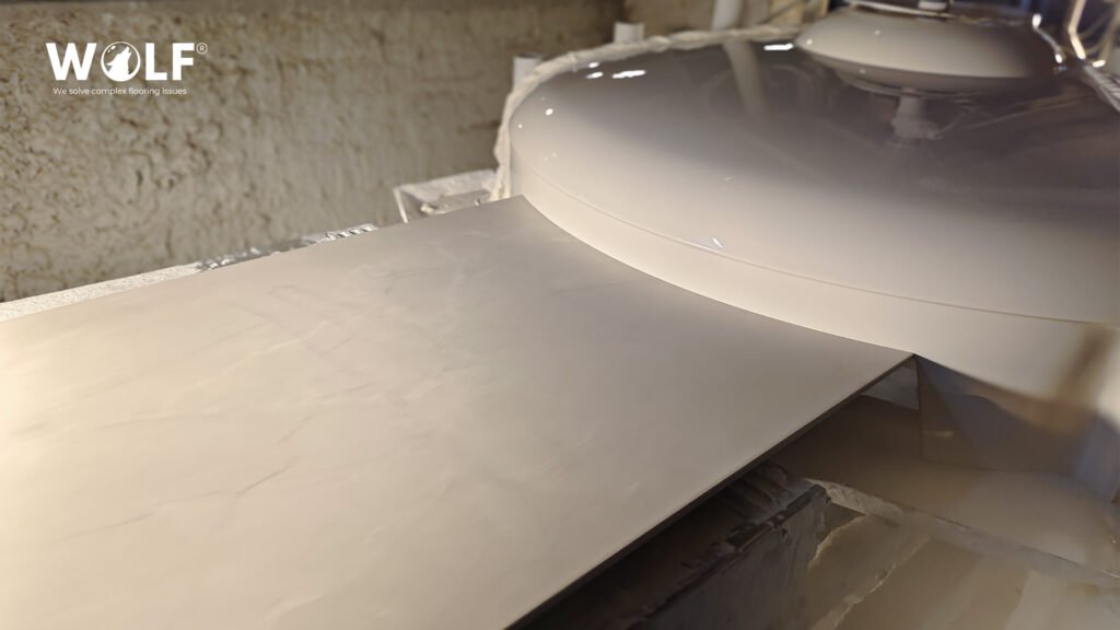 Large porcelain tile slab under the glaze disc on a Wolf production line, part of tile production lead time